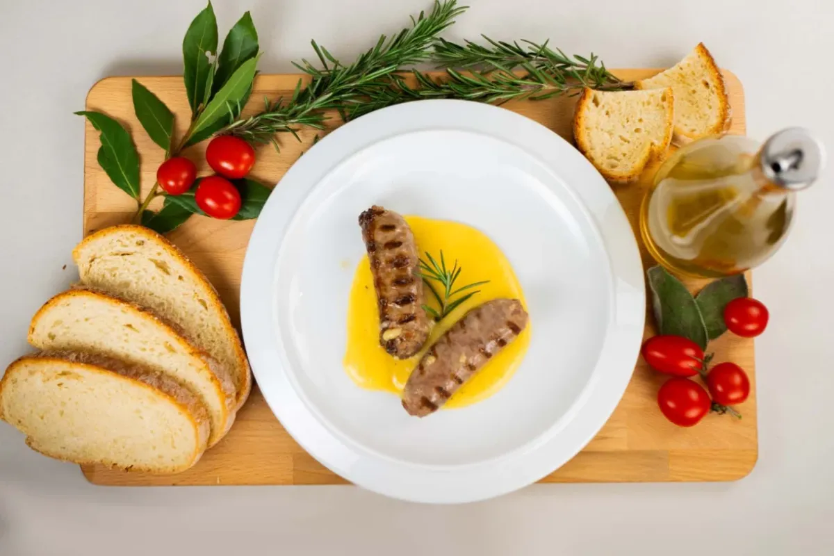 Piatto di salsiccia ripreso dall'alto con contorno di pane e condimenti