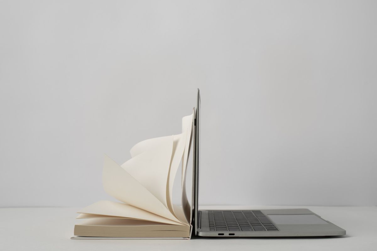 Profilo di un laptop affiancato ad un libro